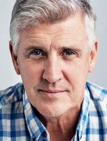 Studio portrait of a mature man posing against a gray background